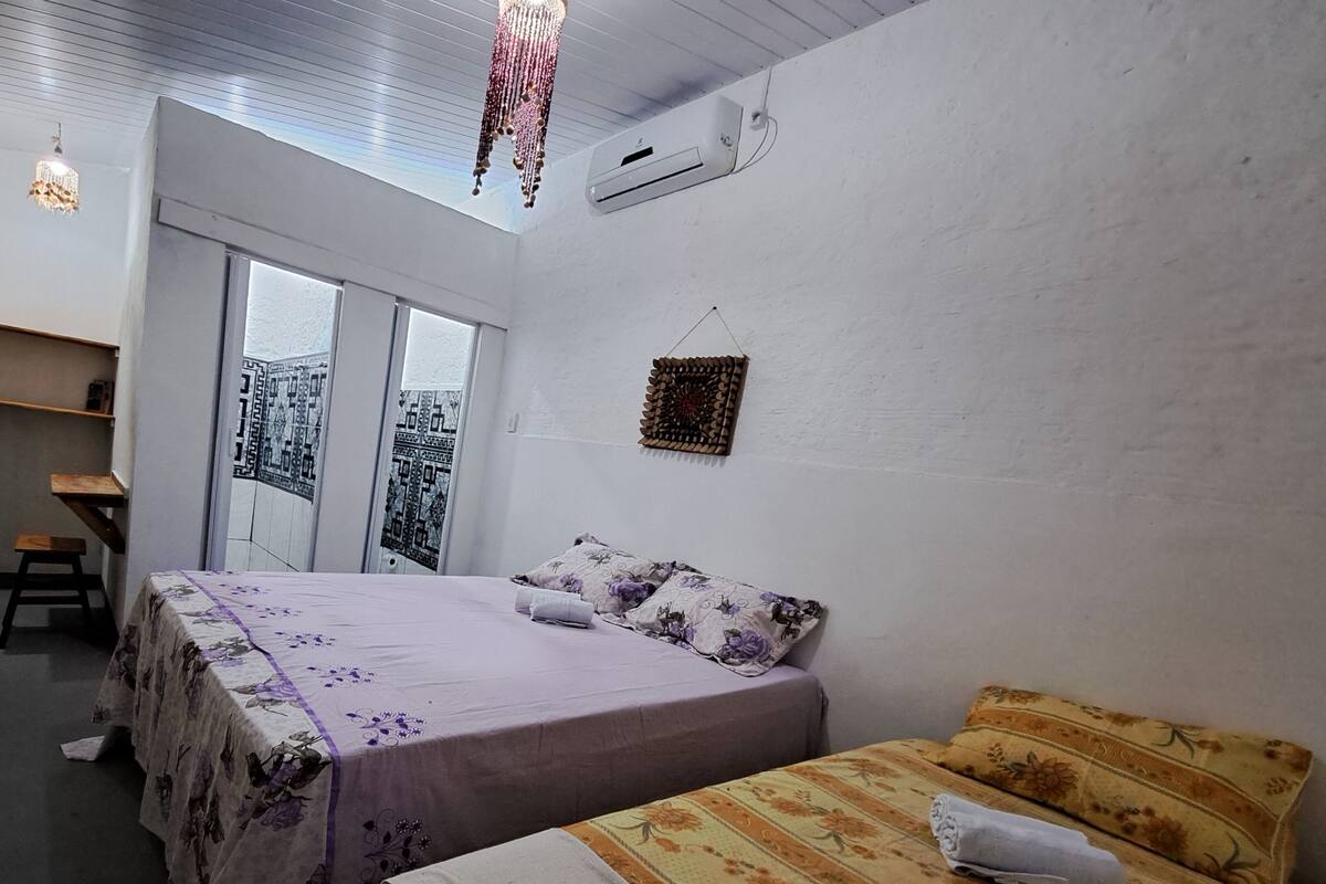 Une chambre avec deux lits, une fenêtre et un ventilateur de plafond.