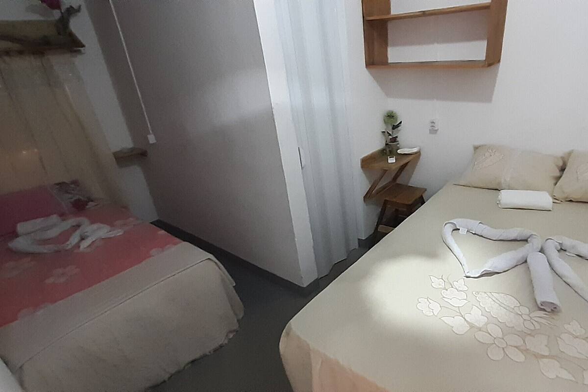 Une chambre d’hôtel avec un lit, une table de chevet, une petite plante et une chaise rouge.