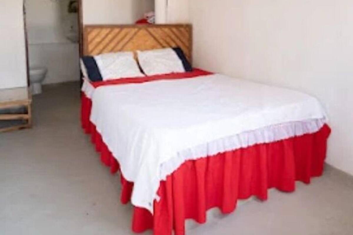 Une chambre à coucher avec un lit, une tête de lit en bois et une couvre-lit rouge et blanche.