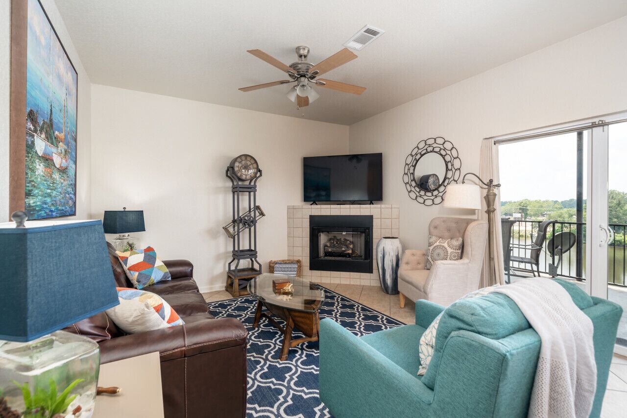 A living room with a fireplace, a television, and a balcony with outdoor furniture.