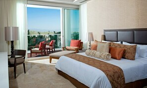 Relax in a spacious room with a large bed, seating area, and a view of the outdoors through a large window.