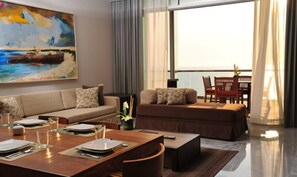 Enjoy a sea view from the comfort of this living room, featuring a sofa set, dining table, and potted plant.