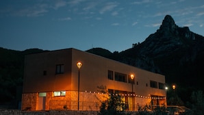 A modern building with a stone base, two visible windows, and a balcony. - Las Ermitas de Vallada (Vallada)