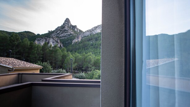 A view from a balcony overlooking a mountainous landscape with a prominent peak, a building with a tiled roof, and a street lamp. - Las Ermitas de Vallada (Vallada)