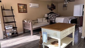 Une pièce chaleureuse avec une table à manger en bois, un canapé, un lit et une échelle appuyée contre le mur.