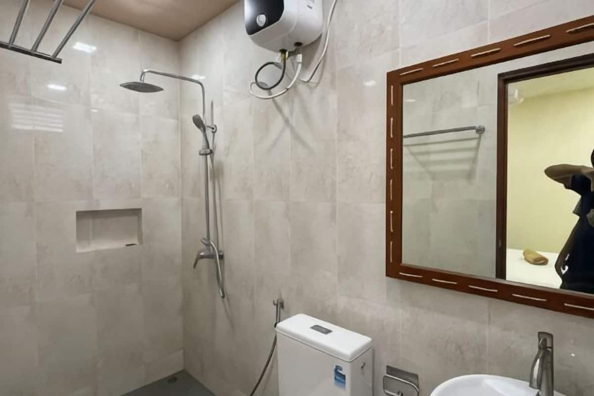 Un baño con ducha, lavamanos, espejo y toallero.