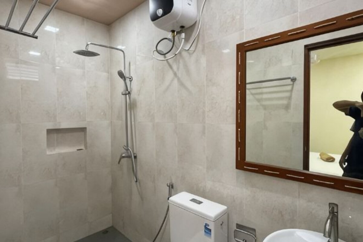 A bathroom with a shower, a sink, a mirror, and a towel rack.