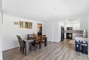 Una cocina moderna con armarios blancos, electrodomésticos de acero inoxidable y piso de madera.