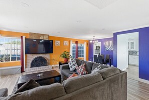 Una sala de estar con chimenea, un sofá, un televisor y un comedor.