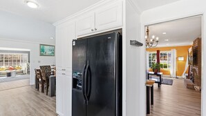 Una cucina moderna con un frigorifero nero, mobili bianchi e un'area pranzo con una panca e sedie.