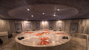 A circular room with a marble floor, a central table, and a patterned ceiling.