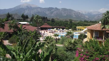 Un resort con piscina, palmeras y montañas al fondo.