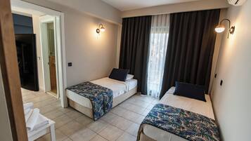 A hotel room with two beds, a small seating area, and a bathroom visible through an open door.
