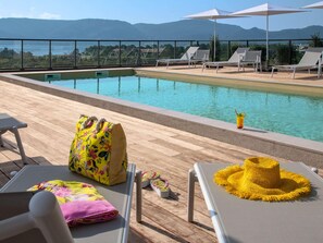 A poolside area with lounge chairs, a pool, and a view of mountains. - Ibis Styles Porto Vecchio (Porto-Vecchio)