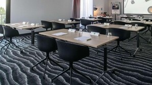 Un salón de conferencias con varias mesas y sillas, tarjetas de identificación y una pantalla para proyector.