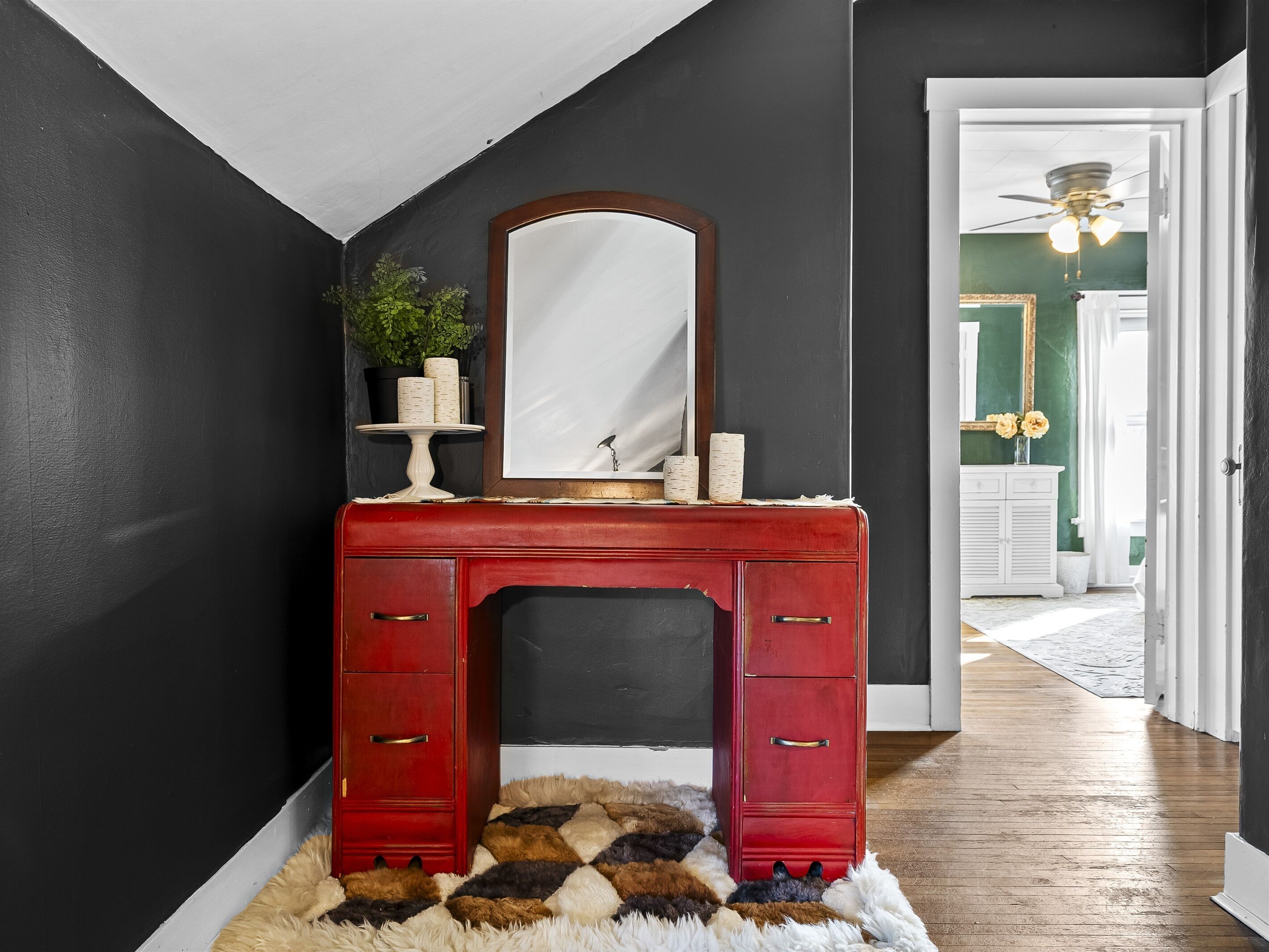 A red dresser with a mirror, a small plant, and decorative items.