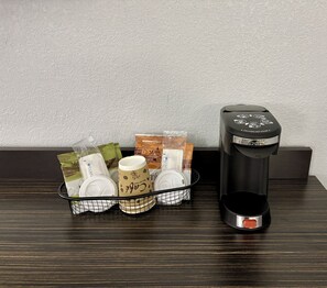 En kaffemaskine og en kurv med kaffekapsler samt en kop på en træoverflade.