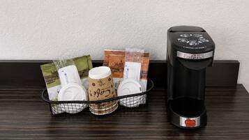 A coffee maker and a basket with coffee pods and a mug on a wooden surface.