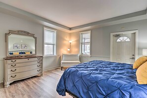 A bedroom with a bed, dresser, chair, and a door.