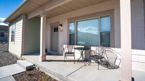 A house with a covered porch, a number 107 sign, and a patio with metal chairs and a table.