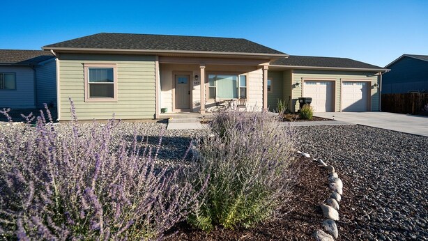 A two-story house with a front porch, a garage, and a well-maintained garden with lavender plants.