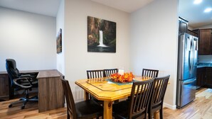 A dining area with a wooden table, six chairs, and a painting on the wall.