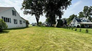 A residential area with houses, a large tree, and a grassy lawn.