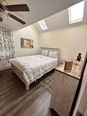 Ein Schlafzimmer mit einem Bett, einem Schreibtisch, einem Deckenventilator und einem Fenster.