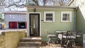 Una casa pequeña con garaje, puerta principal y un patio con mesa y sillas.