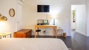 A bedroom with a bed, a desk with a computer, a lamp, and a television on the wall. - The Downtown Abbey - The Drawing Room (San Marcos)