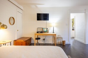 A bedroom with a bed, a desk with a computer, a lamp, and a television on the wall. - The Downtown Abbey - The Drawing Room (San Marcos)