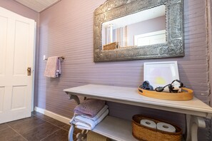 Ett badrum med en tvättställsmöbel, en spegel, handdukar och en korg med hygienartiklar.