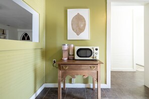 A hallway with a green wall, a framed artwork, a vintage microwave on a wooden table, and a door at the end. - The Downtown Abbey - The Drawing Room (San Marcos)