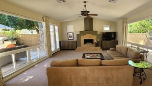 A spacious living room with a fireplace, a large sofa, and a television. - Rancho La Quinta community with amazing pool (La Quinta)