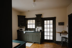 Compact kitchen with a window, microwave, and stool, set in a traditional architectural style.