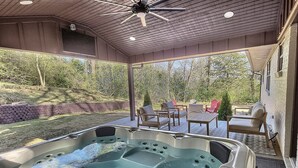 A hot tub area with a ceiling fan, outdoor seating, and a view of the surrounding landscape.