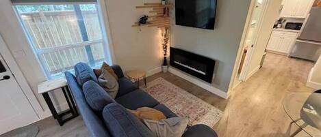 Un salon moderne avec un canapé gris, un téléviseur à écran plat fixé au mur et une cheminée.