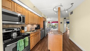 A modern kitchen with wooden cabinets, stainless steel appliances, and a central island. - Bayside Comfort | 2BR Condo with Beach Access & Resort Amenities (Longboat Key)