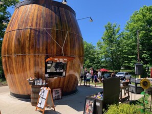 A large wooden barrel structure with a small shop inside, surrounded by greenery and people.