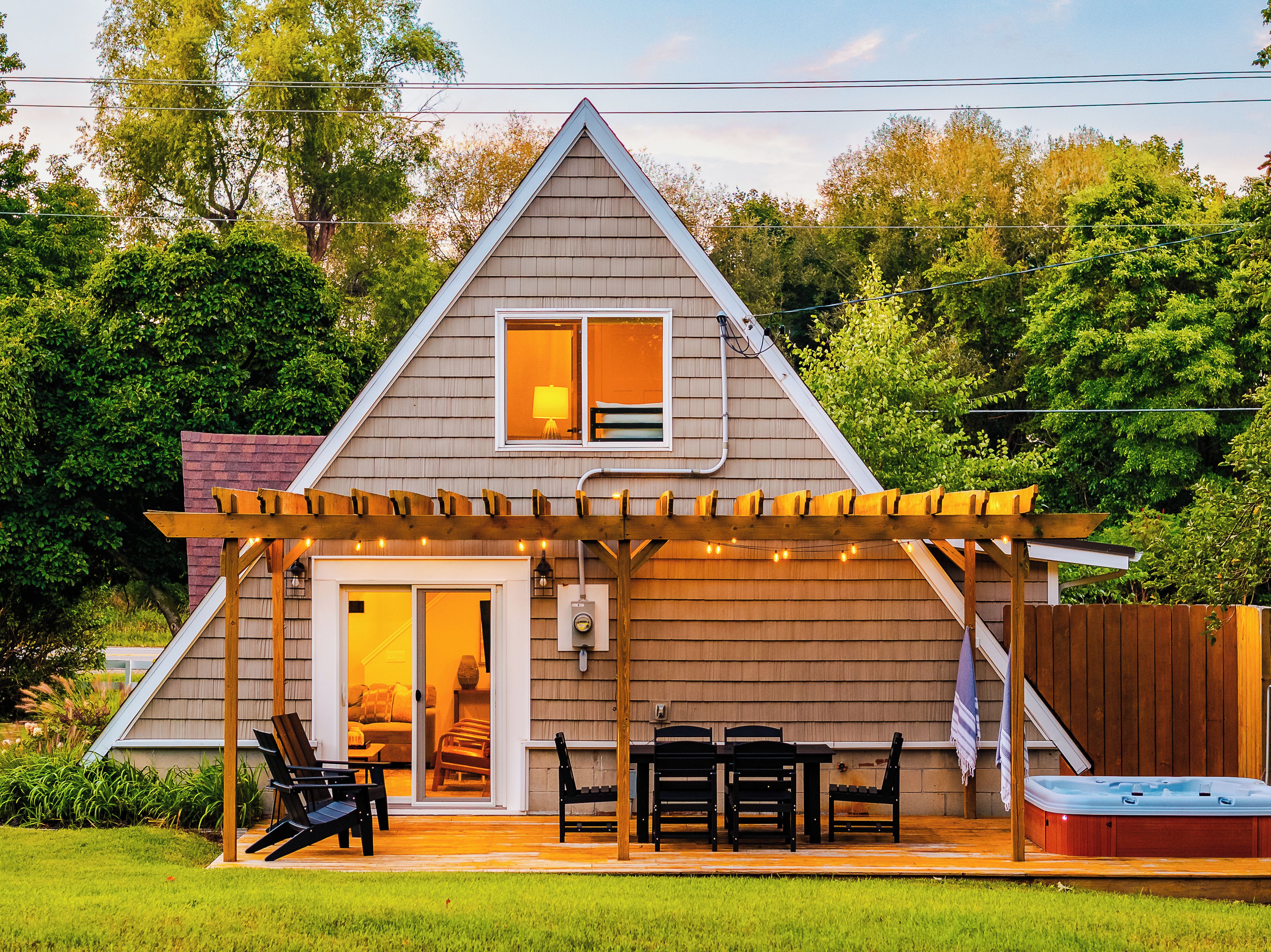 A two-story house with a covered patio, a hot tub, and a dining area.