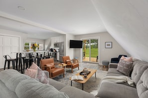 A modern living room with a grey sofa set, a coffee table, and a television. - Applewood Lodge: Private A-Frame with Hot Tub Near Saugatuck & Lake Michigan (Fennville)