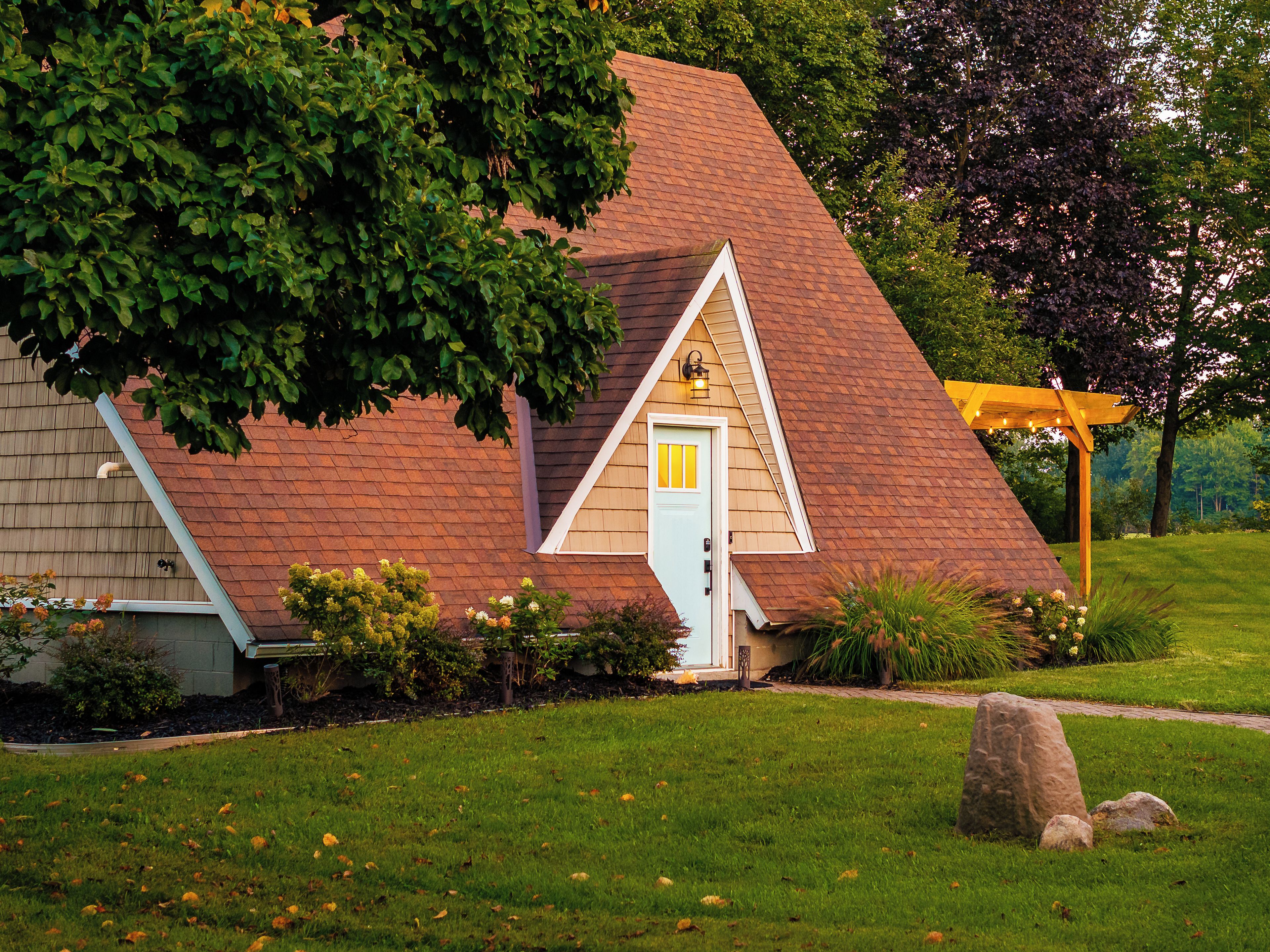 A house with a sloped roof, a front porch, and a well-maintained lawn.