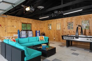 Una habitación con un sofá color turquesa, mesa de billar y mesa de ping pong.