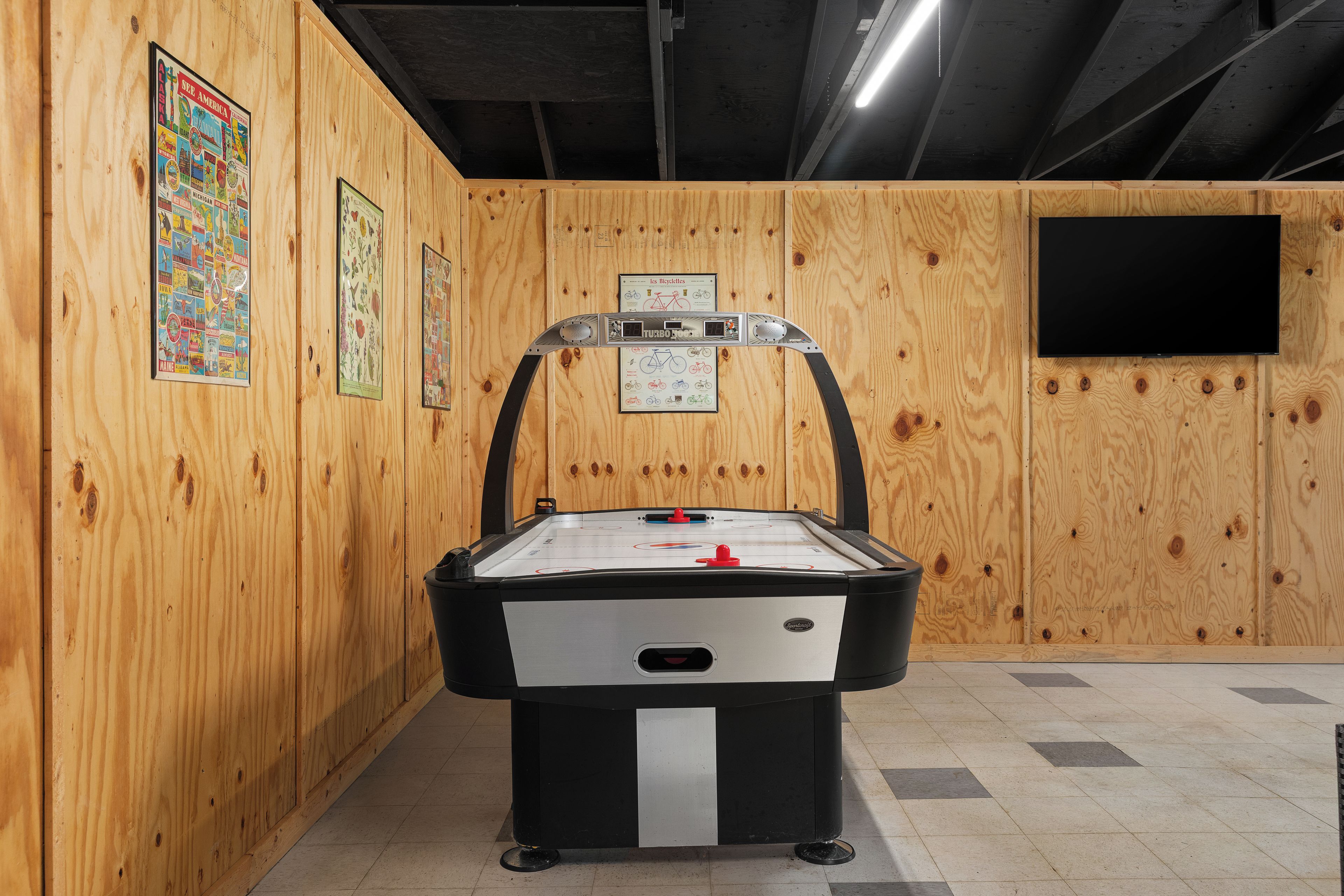 A room with a pool table, wooden walls, and a mounted television.