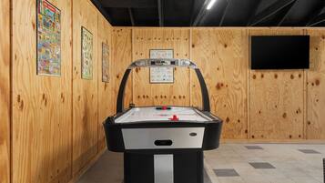 A room with a pool table, wooden walls, and a mounted television.
