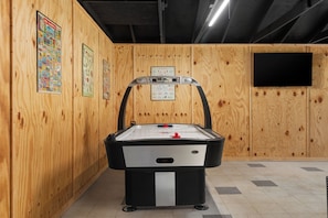 Habitación con mesa de billar, paredes de madera y televisor montado.