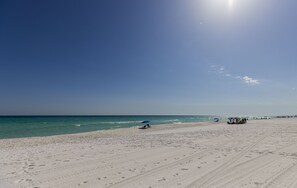 A wide sandy beach with footprints and tire tracks, a clear blue sky, and a calm sea. - Crowe's Nest - Quiet House - Heated Pool - Hot Tub- Walk to Beach -Pet Friendly! (Destin)