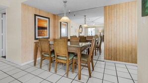 Un coin repas avec des lambris en bois, un grand tableau encadré et un ventilateur de plafond.