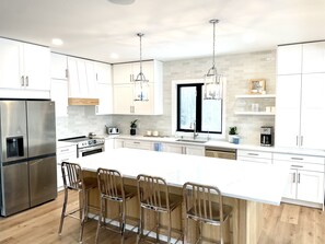 A modern kitchen with white cabinets, stainless steel appliances, and a large island with bar stools.