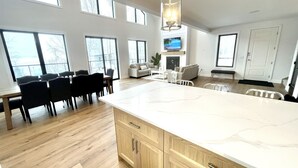A spacious kitchen with a large island, wooden cabinets, and a dining area with chairs.